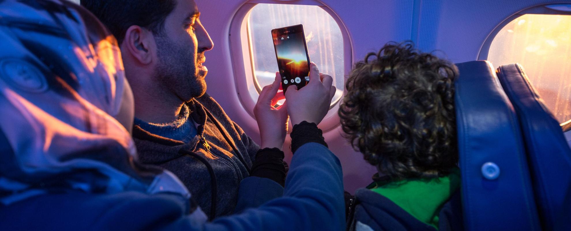 Passagiers nemen een foto door het vliegtuigraampje © IOM/Muse Mohammed 2015