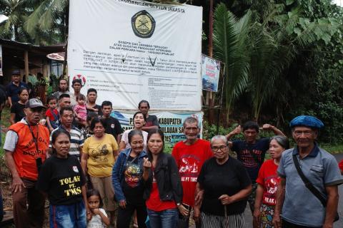  Eilandbewoners voor een spandoek met de print van het arrest van de rechtbank in Jakarta